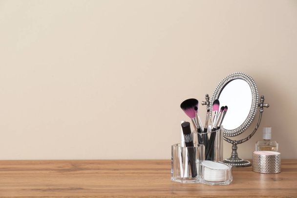 Organizer with makeup cosmetic products and mirror on table against light wall. Space for text - Zdjęcie, obraz