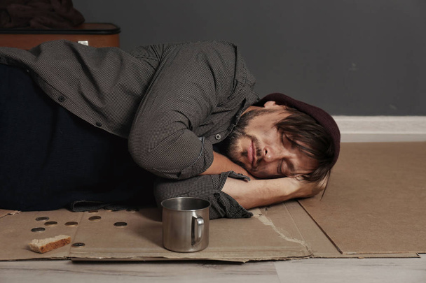 Poor homeless man sleeping on floor near dark wall - Fotografie, Obrázek