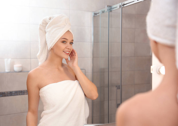 Beautiful woman with clean towels near mirror in bathroom - Photo, Image