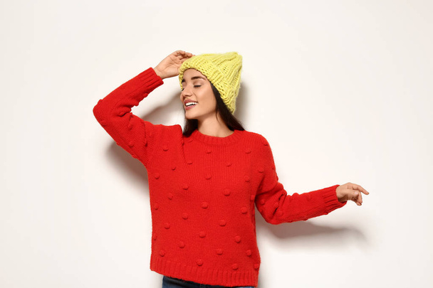 Young woman in warm sweater and hat on white background. Celebrating Christmas - Фото, зображення