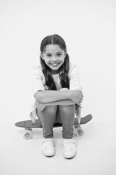 Happy girl sit on penny board on yellow background. Little child smile with long hair on skateboard. Beauty salon. Style and energy. Skills on the wheels - Zdjęcie, obraz