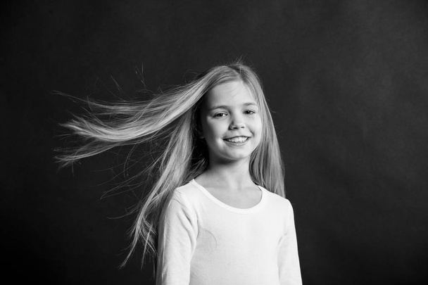 Little girl smile with long blond hair on black background. Happy child with fashion hairstyle. Beauty kid smiling with adorable look. Beauty salon. In this salon we love hair - Fotoğraf, Görsel