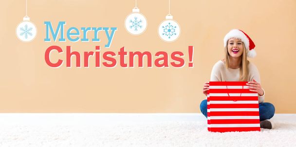 Merry Christmas message with woman with Santa hat holding a shopping bag - Photo, image