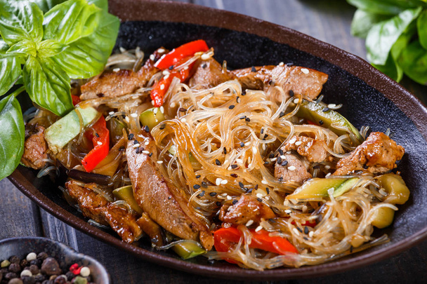 Rice noodles with meat, vegetables and sesame seeds on wooden table. Indian cuisine. Top view. - Photo, Image