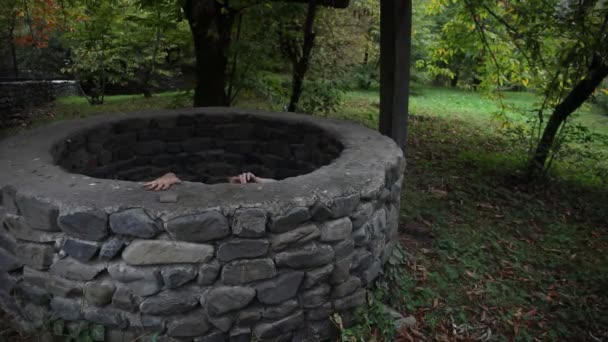 A terrible girl with long black hair is standing in a gloomy well. Scary Halloween photo. Dead zombie girl climbs out of the well - Footage, Video