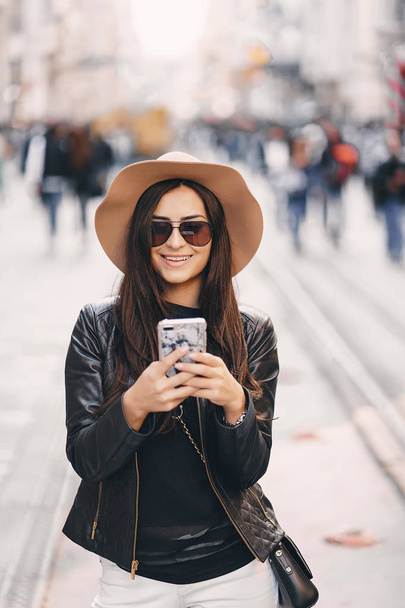 stylish girl in brown hat using phone in istanbul turkey - Foto, Imagen