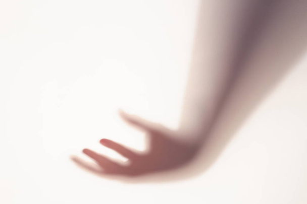 The concept of the shadow of hand behind frosted glass illuminated from behind. - 写真・画像