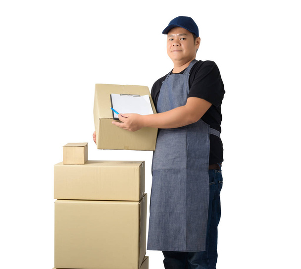 Full Body portrait of delivery man in Black shirt and apron with stack of boxes is carrying parcel and presenting receiving form isolated on the white background with clipping path - Фото, изображение