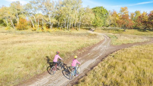 Familia en bicicletas otoño ciclismo al aire libre, madre activa y el niño en bicicletas, vista aérea de la familia feliz con el niño en el parque de otoño desde arriba, el deporte y el concepto de fitness - Foto, imagen