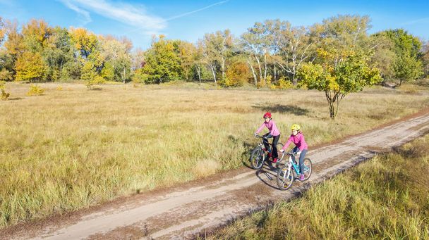Family on bikes autumn cycling outdoors, active mother and kid on bicycles, aerial view of happy family with child in fall park from above, sport and fitness concept - Photo, Image