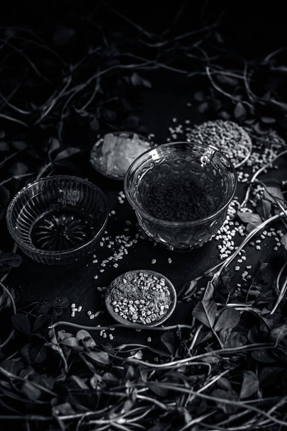 Fenugreek tea with honey, fenugreek leaves and seeds on a wooden surface in dark Gothic colors  - Фото, зображення