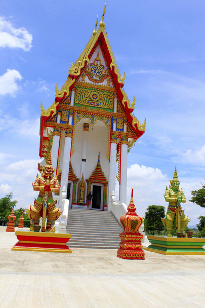 Vista frontal do templo vermelho e branco com os guardas e degraus que levam ao ídolo principal no interior em Buang Sam Phan, Phetchabun, Tailândia
 - Foto, Imagem