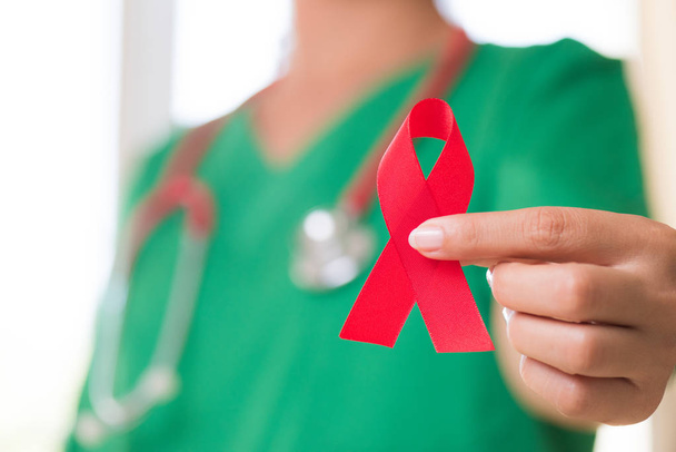 Nainen lääkäri stetoskooppi olkapää tilalla punainen nauha HIV, maailman AIDS päivä tietoisuutta nauha. Terveydenhuollon ja lääketieteen käsite
. - Valokuva, kuva