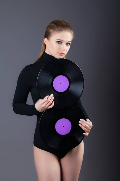 A beautiful girl is holding two vinyl discs. Studio shot on a gray background. - Fotoğraf, Görsel