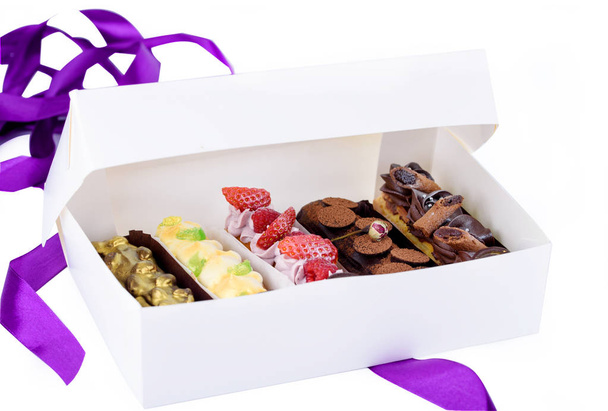 eine Schachtel leckerer Desserts. Eclairs mit unterschiedlichen Füllungen. köstliche Desserts in der Verpackungsbox. - Foto, Bild