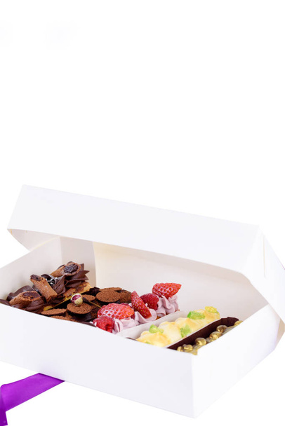 eine Schachtel leckerer Desserts. Eclairs mit unterschiedlichen Füllungen. köstliche Desserts in der Verpackungsbox. - Foto, Bild