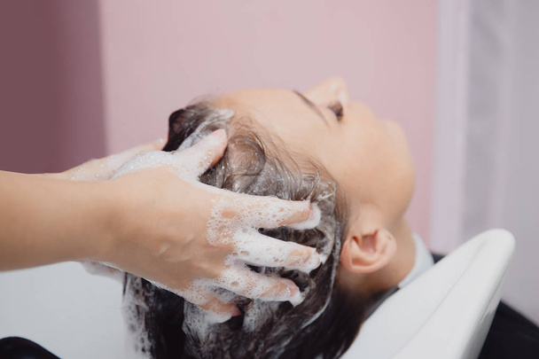 Master peina el cabello al cliente para el procedimiento de restauración en el salón
 - Foto, imagen