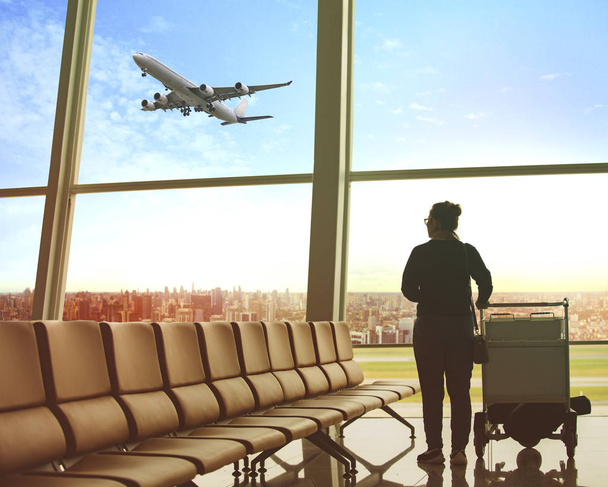 single woman sitting in airport terminal and passenger plane flying outdoor for traveling theme - Photo, Image