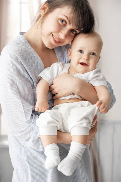 Happy baby in mother's arms in her room - Foto, afbeelding