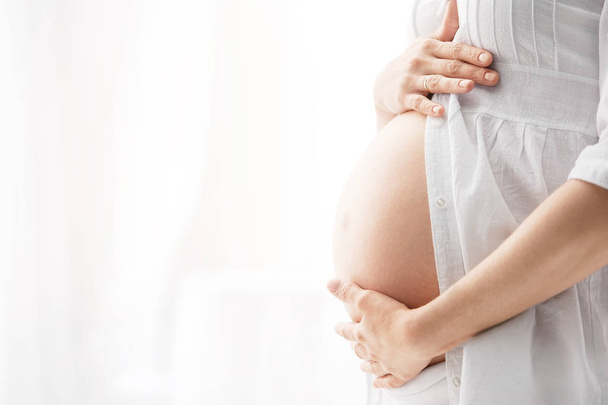 Eine schwangere Frau, ihre Hände sanfte Umarmung - Foto, Bild
