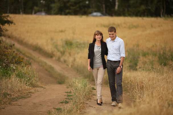 Young man and woman walking in a field of wheat - Foto, Imagen