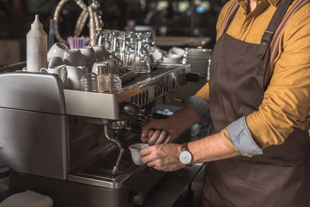 cropped shot of professional barista preparing coffee with coffee machine in cafe - Foto, Bild
