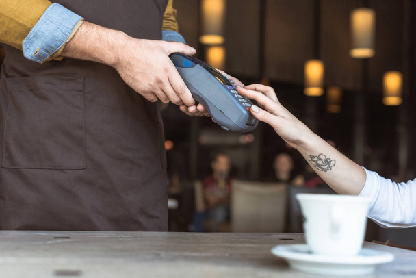 corte tiro de garçom segurando terminal de pagamento enquanto o cliente entrar pino no café
 - Foto, Imagem