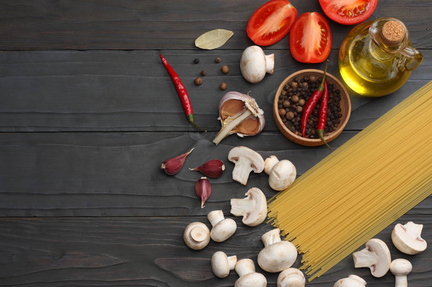 Italian food background, with tomatoes, parsley, spaghetti, mushrooms, oil, lemon, peppercorns on dark wooden table. Top view - Fotoğraf, Görsel