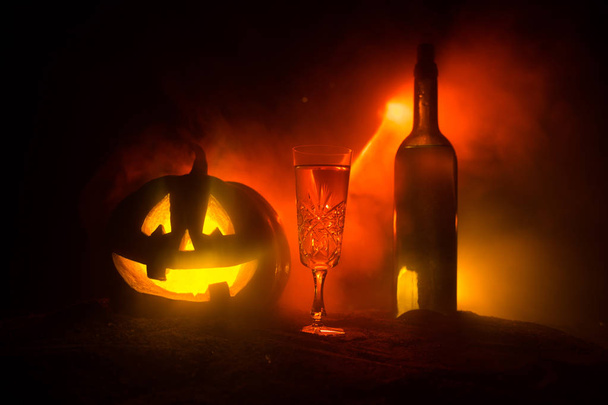 ハロウィーンのワイン パーティーのテーマ。ワインとハロウィーン - 古いジャック-o-ランタン暗いとボトルのガラスは、霧の背景トーン。怖いハロウィーンのカボチャ - 写真・画像