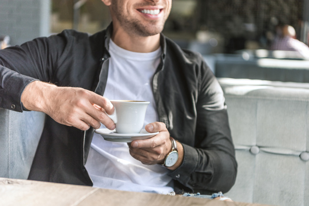 Genç adamın atışta bir kafede oturup kahve kırpılmış - Fotoğraf, Görsel
