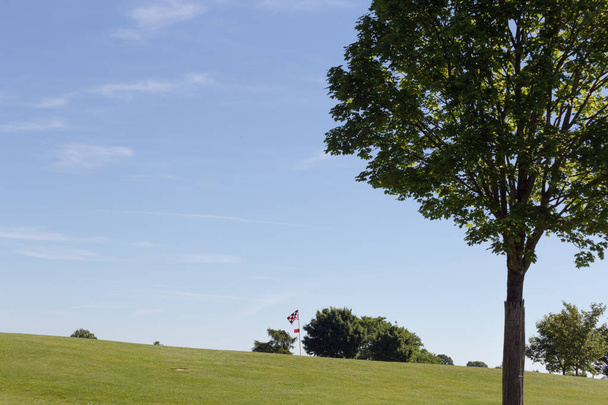 en un día muy soleado en junio en el sur de Alemania se ven campos de golf con verde y jugadores y pelota de golf con banderas y área de arena
 - Foto, Imagen