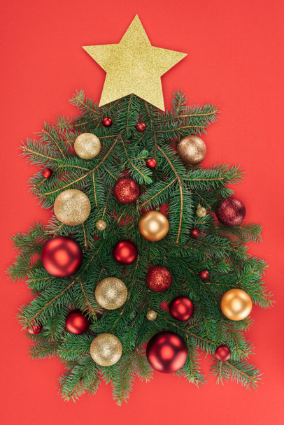 vista superior de ramas de pino, estrella dorada y bolas de navidad dispuestas en árbol de navidad aislado en rojo
 - Foto, Imagen