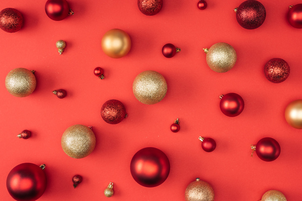 Draufsicht auf rote und goldene dekorative Weihnachtskugeln isoliert auf rot - Foto, Bild
