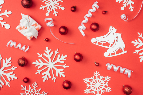 acostado plano con copos de nieve decorativos blancos, cintas, juguetes de Navidad rojos y regalo envuelto aislado en rojo
 - Foto, imagen