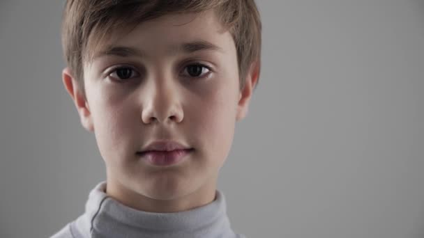 Gros plan Portrait de mignon jeune garçon de 11 - 12 ans regardant la caméra sur fond blanc
 - Séquence, vidéo
