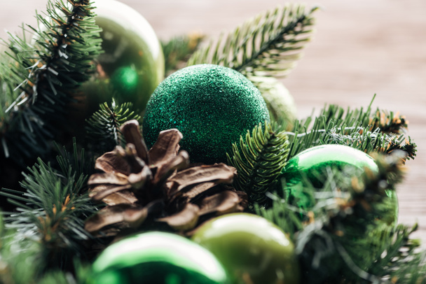 κλείνω πάνω θέα του πεύκο δέντρο στεφάνι με πράσινα Χριστούγεννα μπάλες σε φόντο ξύλινη - Φωτογραφία, εικόνα