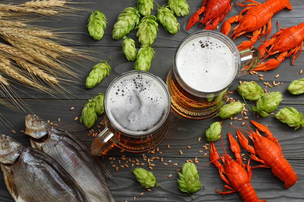 Glass beer with crawfish, dried fish and wheat ears on dark wooden background. Beer brewery concept. Beer background. top view with copy space - Foto, afbeelding