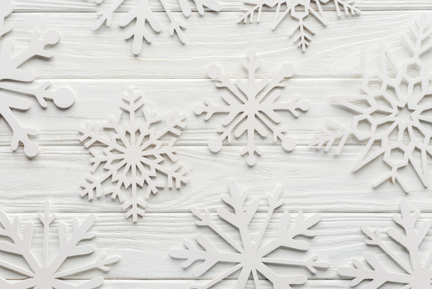 Beyaz ahşap masa üzerinde dekoratif kar taneleri ile düz lay - Fotoğraf, Görsel