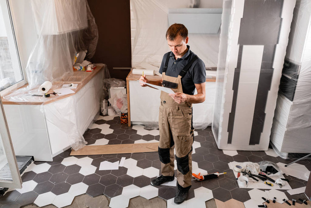 Focused diligent worker inspecting room and planning repairs work. repair of the dining room in the house, kitchen furniture, floor covering change - Valokuva, kuva