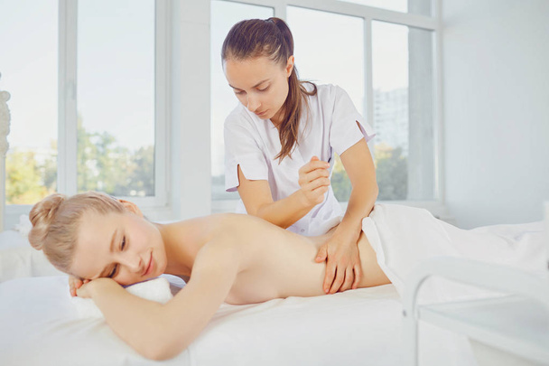 Body massage. Blond woman in spa salon doing body massage. - Foto, immagini