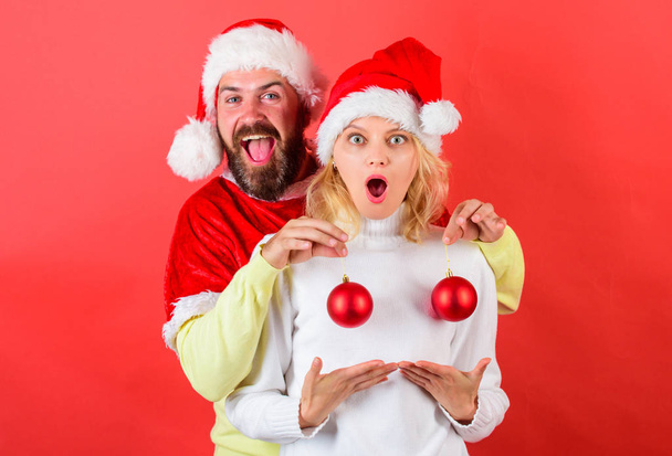 Man santa hat hold balls christmas ornament in front of female breasts. Christmas balls symbol implant female breasts. Couple excited hold christmas balls. Christmas miracle concept. Plastic surgery - Photo, image