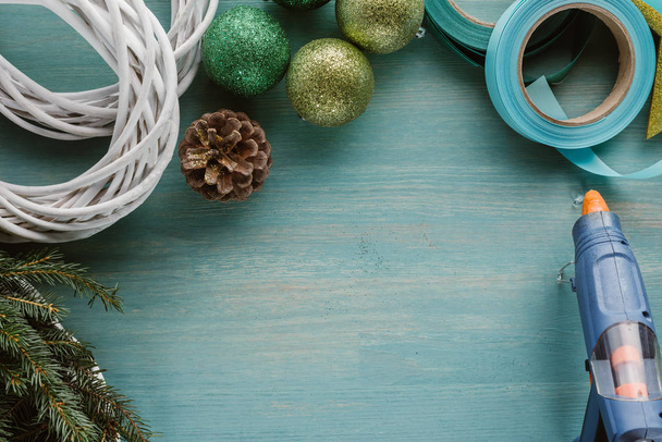 pohled shora lepicí pistole a dekorací pro ručně vyráběné vánoční věnec na modré dřevěný povrch - Fotografie, Obrázek
