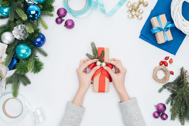 vue partielle de la femme décorant le cadeau enveloppé avec des boules de Noël isolées sur blanc
 - Photo, image