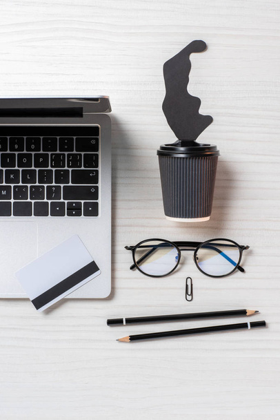 płaskie lay z laptopa, karta kredytowa, okulary i filiżanka kawy jednorazowe przy stole w biurze  - Zdjęcie, obraz