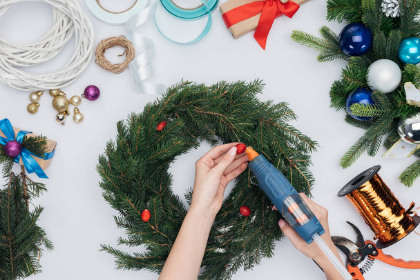 tiro cortado de mulher decorando grinalda de Natal artesanal com bagas de briar isolado no branco
 - Foto, Imagem