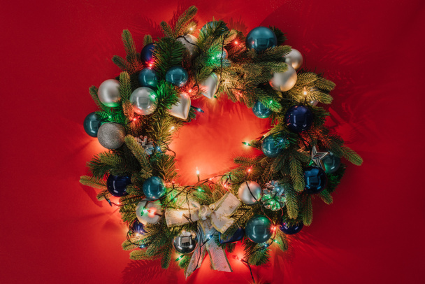 vista superior de la corona de Navidad decorada con juguetes y luces sobre fondo rojo
 - Foto, imagen