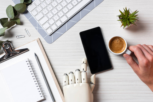частковий вид на бізнесмена з протезом рукою за допомогою смартфона з порожнім екраном за столом з чашкою кави в офісі
  - Фото, зображення