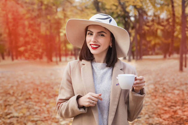 Menina bonita com xícara de café no parque de outono
. - Foto, Imagem