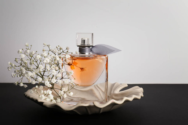 Flacon transparent de parfum avec de belles fleurs sur table noire
 - Photo, image