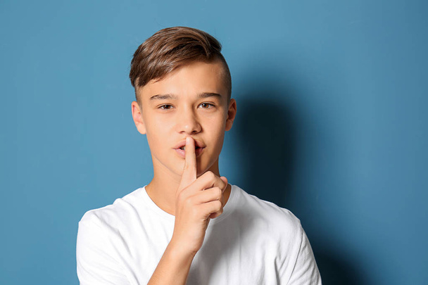 Teenage boy showing silence gesture on color background - Foto, Bild